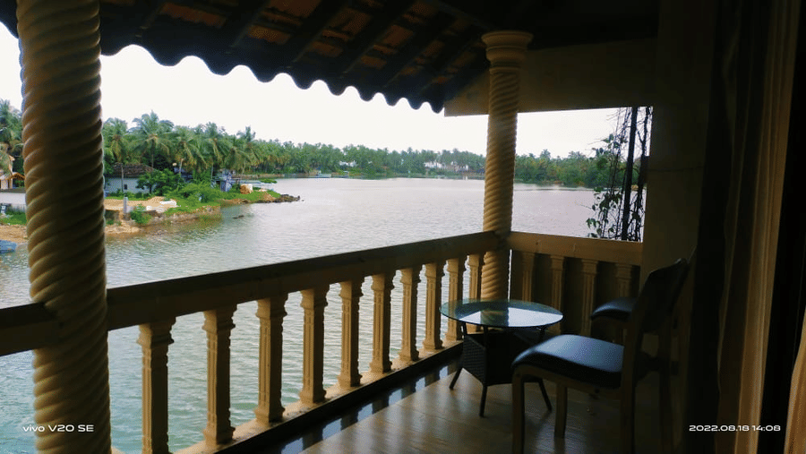 Balcony overlooking the water with chairs and table  with fence at Paradise Lagoon Resort, Udupi.