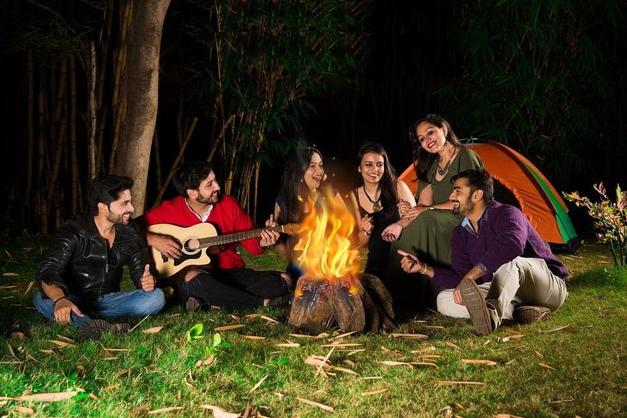 Group of Friends sitting in a circle around a fire camp