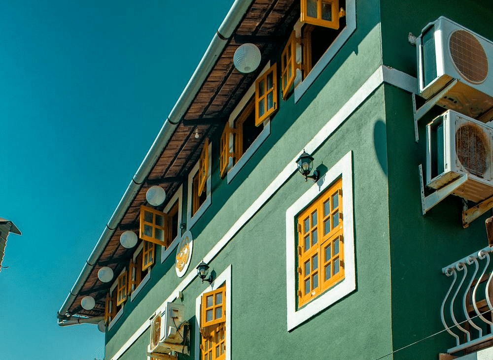 A beautifully painted green colonial-style building with arched windows and balconies, set against a clear blue sky.