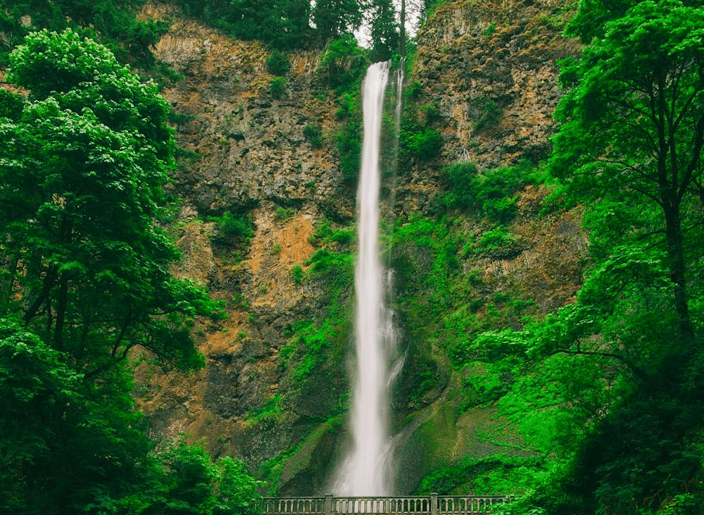 Image of a waterfall and a bridge in front of it.