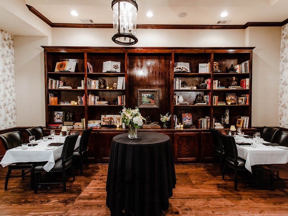 A  library with bookshelves, elegant seating, and a round table in the center, creating a sophisticated reading space.- The Grand Hotel & Ballroom, McKinney