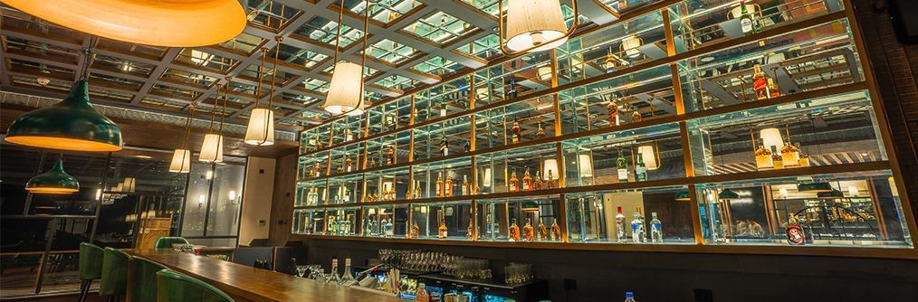 A wide angle image capturing the bar counter and the wide collection of beverages available at The Grand Bar - Polo Hotel Agartala