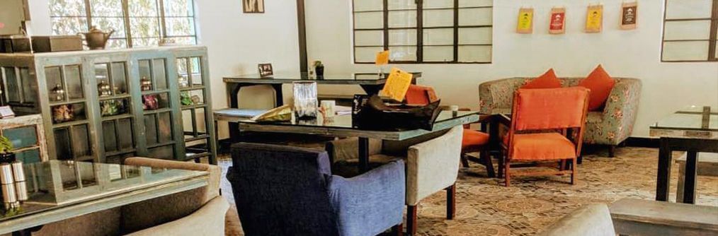 A panoramic shot of a cosy lounge and seating area with bookshelves at the Polo Hotel Shillong.