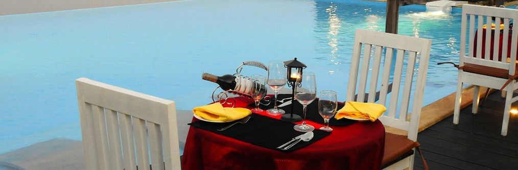 A poolside dining setup at Polo Resort Cherrapunjee with a red-clothed table and chairs by the swimming pool.