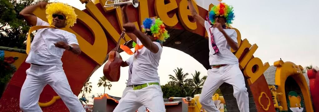 three men with colourful hair dancing in front of MGM Dizzee World's entrance