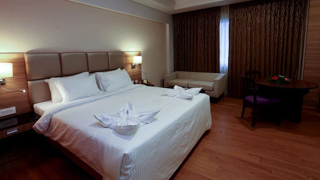 Side view of room with bed, sofa and table with chair at Fressotel Seetharam, Coimbatore