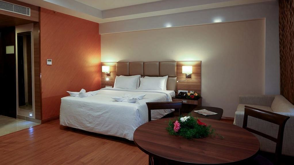 Room with bed and a table with flowers on top at Fressotel Seetharam, Coimbatore