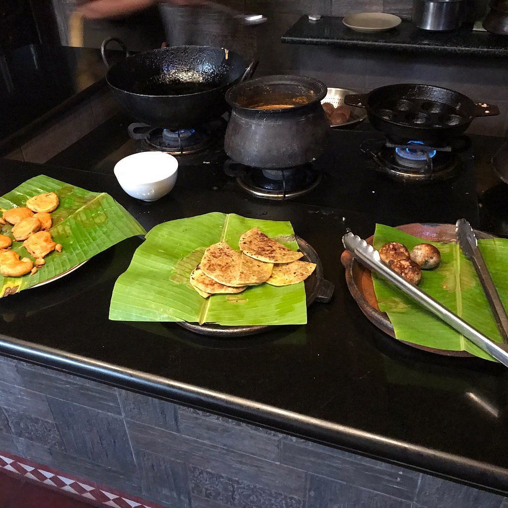 image of food plated on banana leaves with three black earthen pots on the stove at Hoysala Village Resort, Hassan
