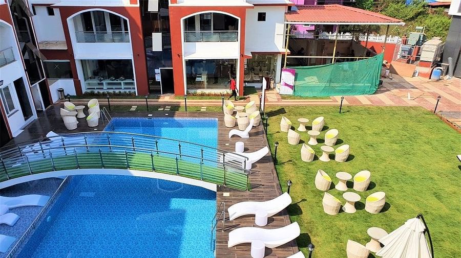 swimming pool, loungers and seating arrangements on the grass at VITS shanti solitaire, North Goa