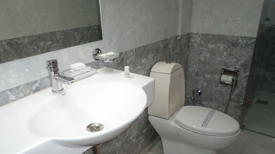 Bright bathroom with a large sink, toilet, and glass partition