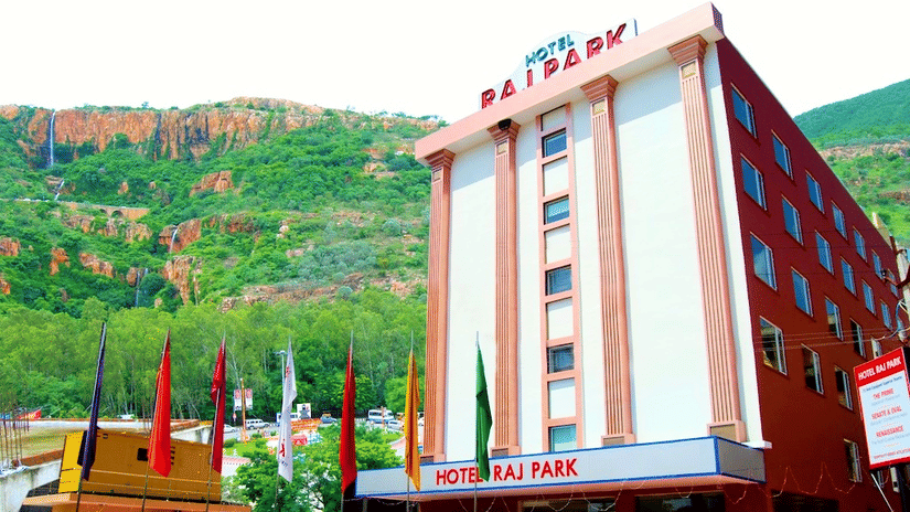 Facade of Raj Park Hotel, Tirupati, with a green mountain in the background.