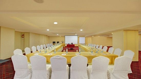 Chairs arranged around a big U shaped table for conference purposes, with limited decorations and a white screen at the front for the presenter - Monarch Hotels