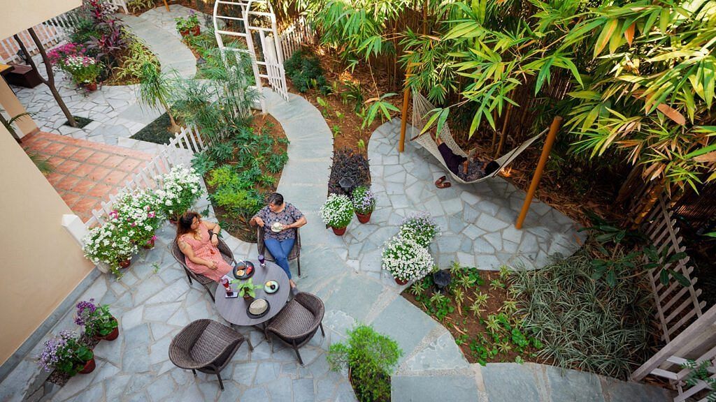 Aerial view of a landscaped garden courtyard with pathways, seating areas, and potted plants in a residential setting at Karma Chalets.