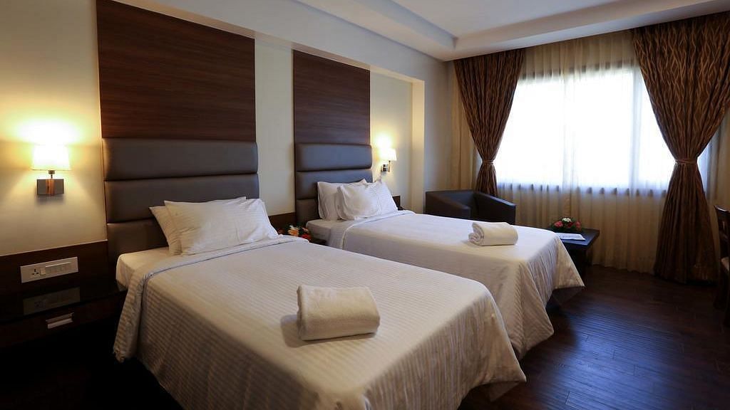 Room wtih twin beds and lamps on both sides on the bed at Fressotel Seetharam, Coimbatore