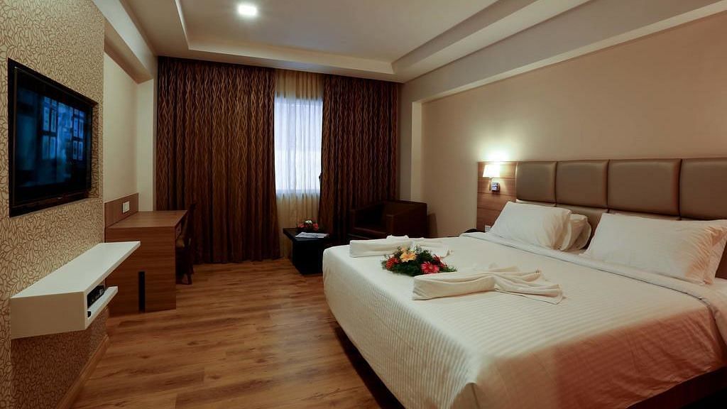 Spacious room with television, bed and table at Fressotel Seetharam, Coimbatore