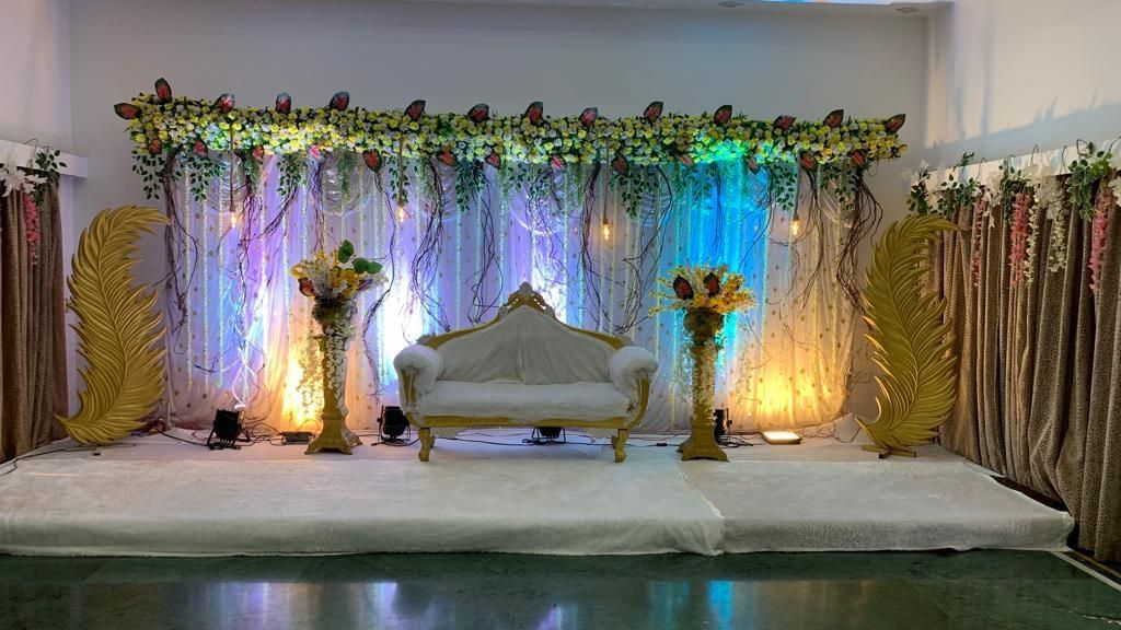 Floral stage setup with soft lighting and golden curtains, ideal for weddings and special events at Mayur Retreat.
