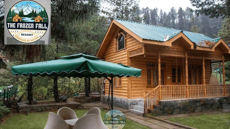 Exterior view of a wooden cottage at Dawat e Drung by FrozenFall Resort, Drung, Tangmarg, featuring an outdoor seating table under an umbrella canopy.