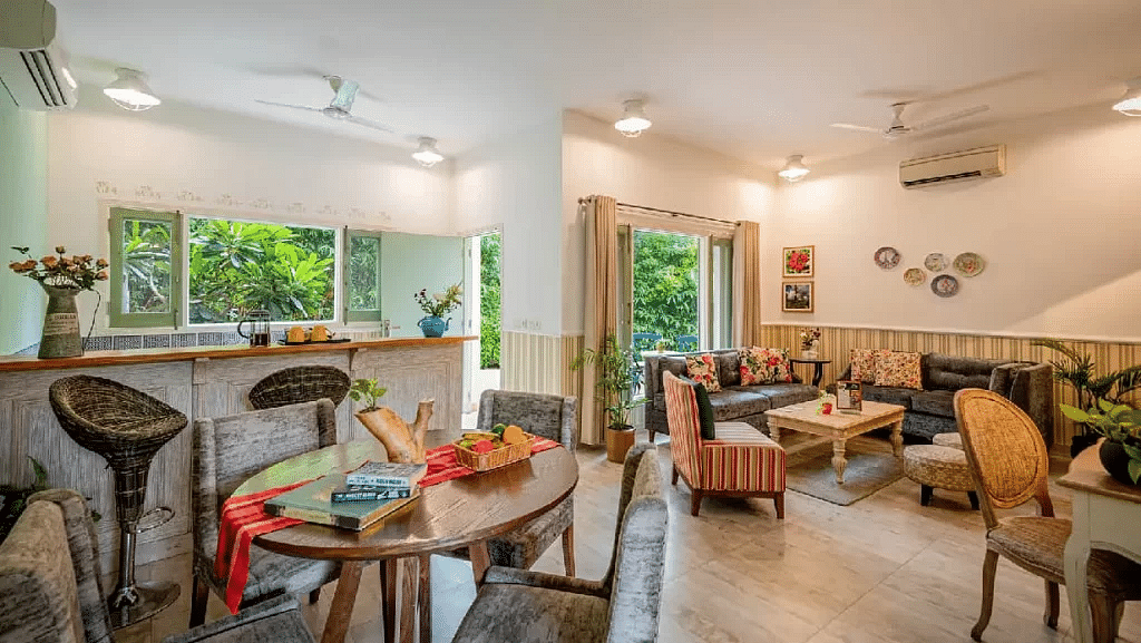 Dining area with multiple tables and chairs, light-colored walls, and large windows letting in natural light at Karma Chalets. 
