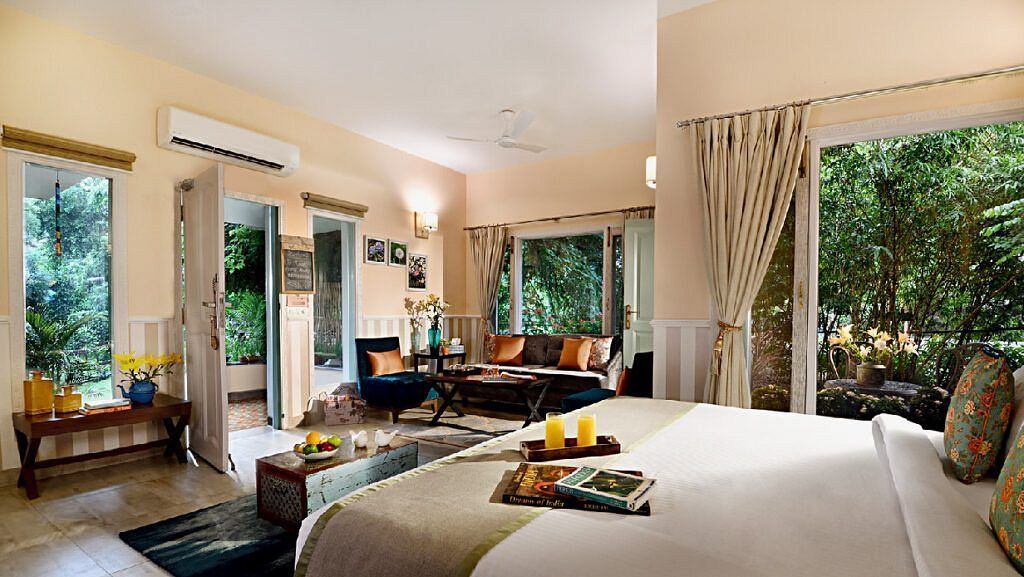 Spacious bedroom with a large bed, seating area, glass doors, and greenery visible outside at Karma Chalets.