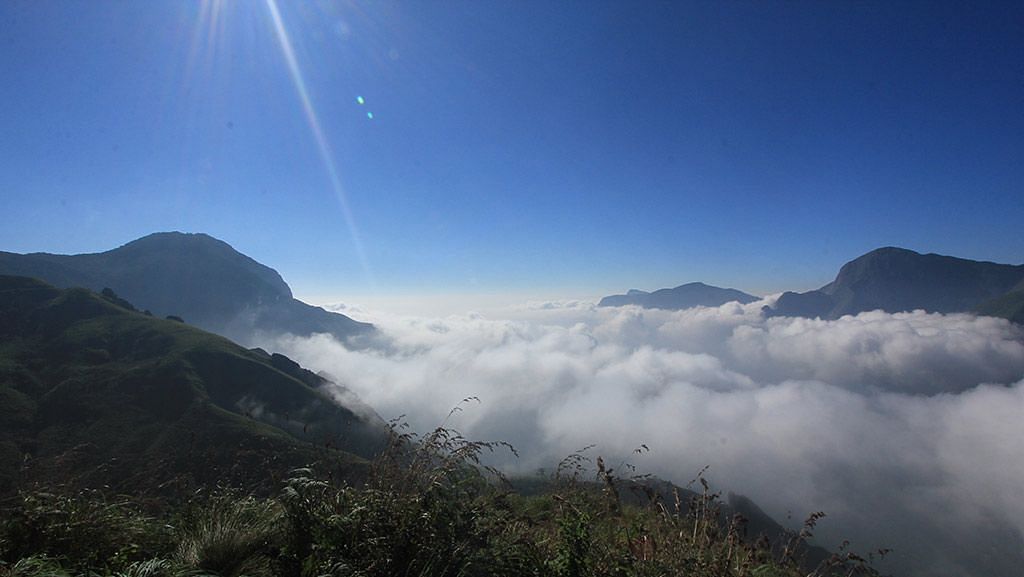 Mountains shrouded in mist with sun rays illuminating them, creating a stunning view