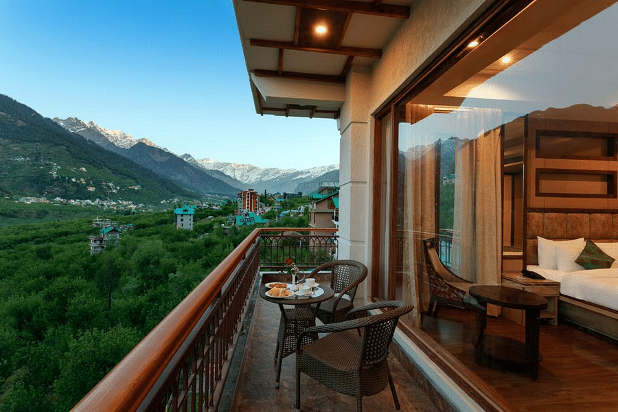 Suite in Manali with an attached balcony overlooking the mountains and greenery