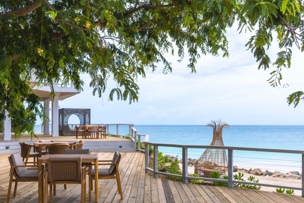 Open-air beachfront dining area under lush greenery at Tamarind Hills Resort and Villas, offering stunning ocean views and a relaxed tropical vibe.