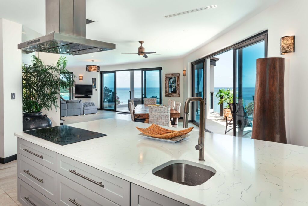 A spacious modern kitchen with a large island, stainless steel appliances, and ocean views.