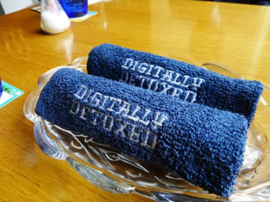 Blue towels with 'Digitally Detoxed' text rolled and displayed in a bowl