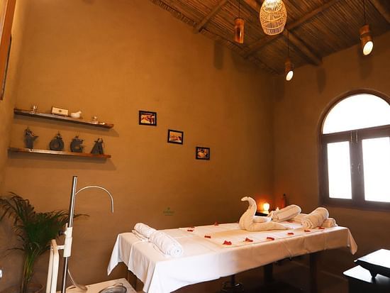 Themis Medival Wellness Centre displaying a massage table and rustic interior at Themis Mudhouse - A Nature's Retreat Resort & Wellness, oen of the best ayurvedic spa resorts near delhi