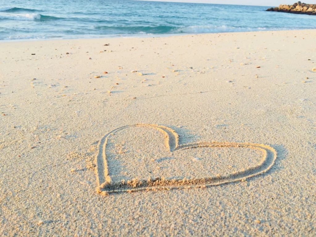 A heart drawn in the sand on a peaceful, empty beach with gentle waves and golden sunlight - Tamarind Hills Resort and Villas - Antigua
