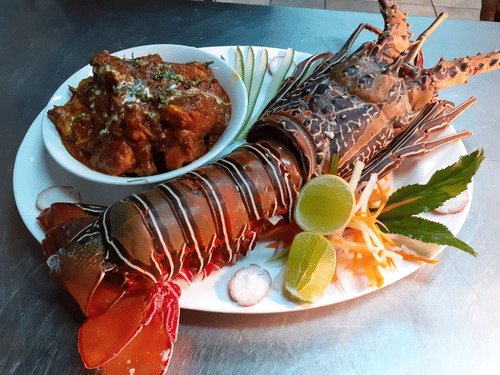 A cooked lobster on a plate with garnishes