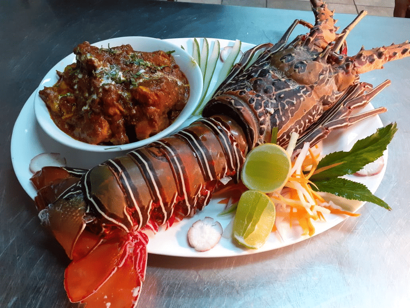A cooked lobster on a plate with garnishes