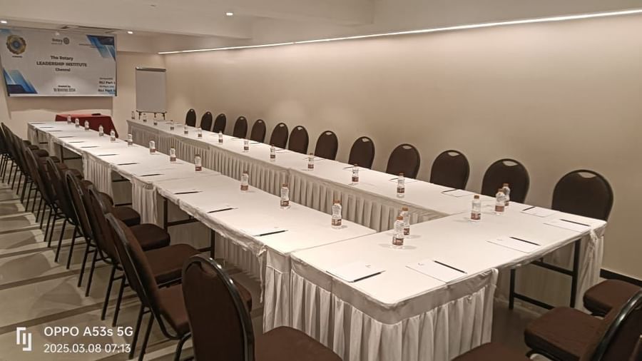 A long  u-shaped conference table with white tablecloths and chairs, prepared for a business event at Shilton Dee Cee.