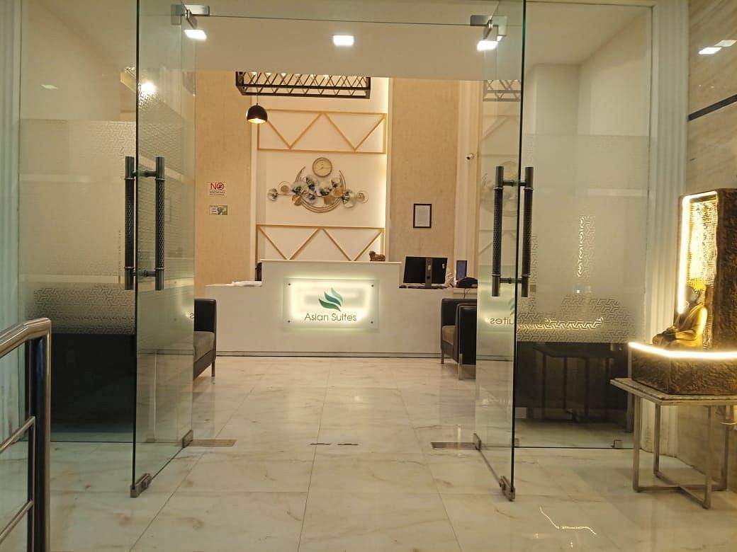 A modern entrance with glass doors and decorative wall panels leads into a brightly lit interior space - Asian Suites Cyber Park, Gurgaon