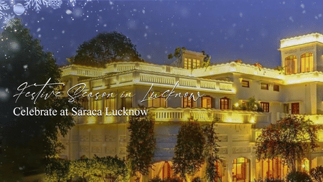 Illuminated heritage-style facade of Saraca Hotels & Resorts at night, surrounded by trees under an evening sky.