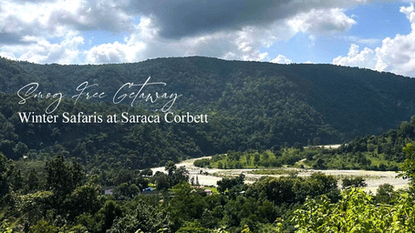Scenic landscape of a resort nestled among rolling green hills under a clear blue sky, highlighting a tranquil nature retreat, with Smog Free Break Saraca Corbett written on the image.