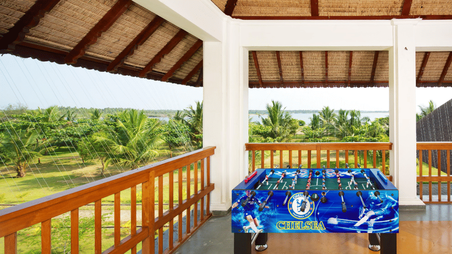 A covered outdoor balcony area with a wooden railing featuring a blue foosball table | Le Pondy