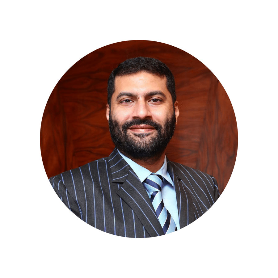 Formal portrait of Dr. Vikram Kamat, Chairman and Founder of VITS Kamat Group, wearing a dark pinstripe suit, light blue shirt, and striped tie.