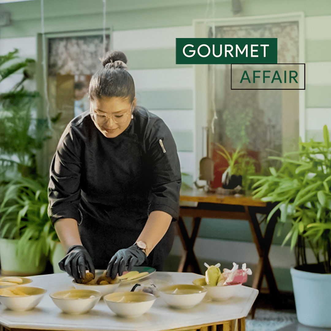 A chef carefully decorates a dish with precision, surrounded by lush indoor plants that provide a vibrant, indoor plant backdrop.