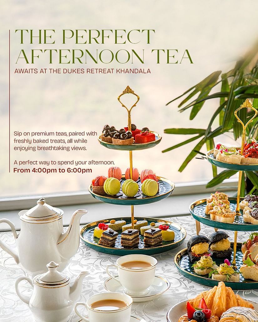 Afternoon tea setup with elegant teapots, cups, and a three-tier stand filled with colorful macarons, pastries, and savory treats at The Dukes Retreat Khandala