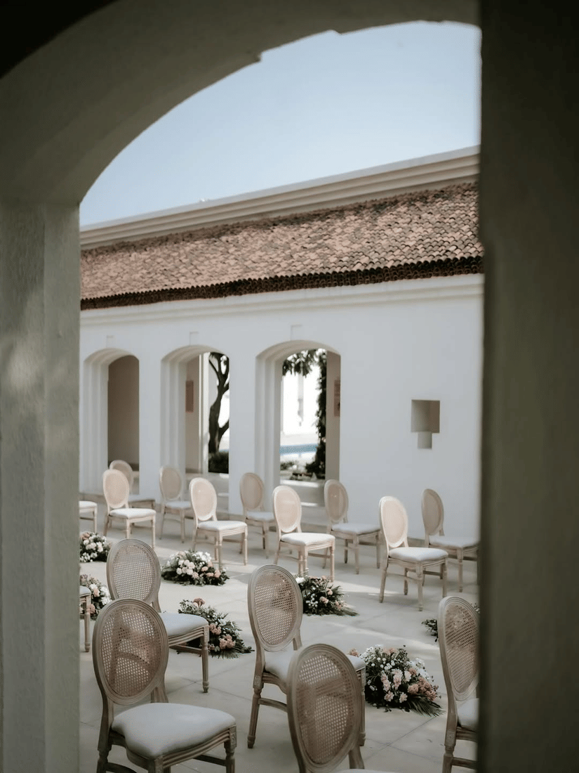Courtyard seating at Marasa Sarovar Premiere, Bodhgaya with arranged chairs, floral aisle accents, arched corridors, tiled roof, and open-air setting