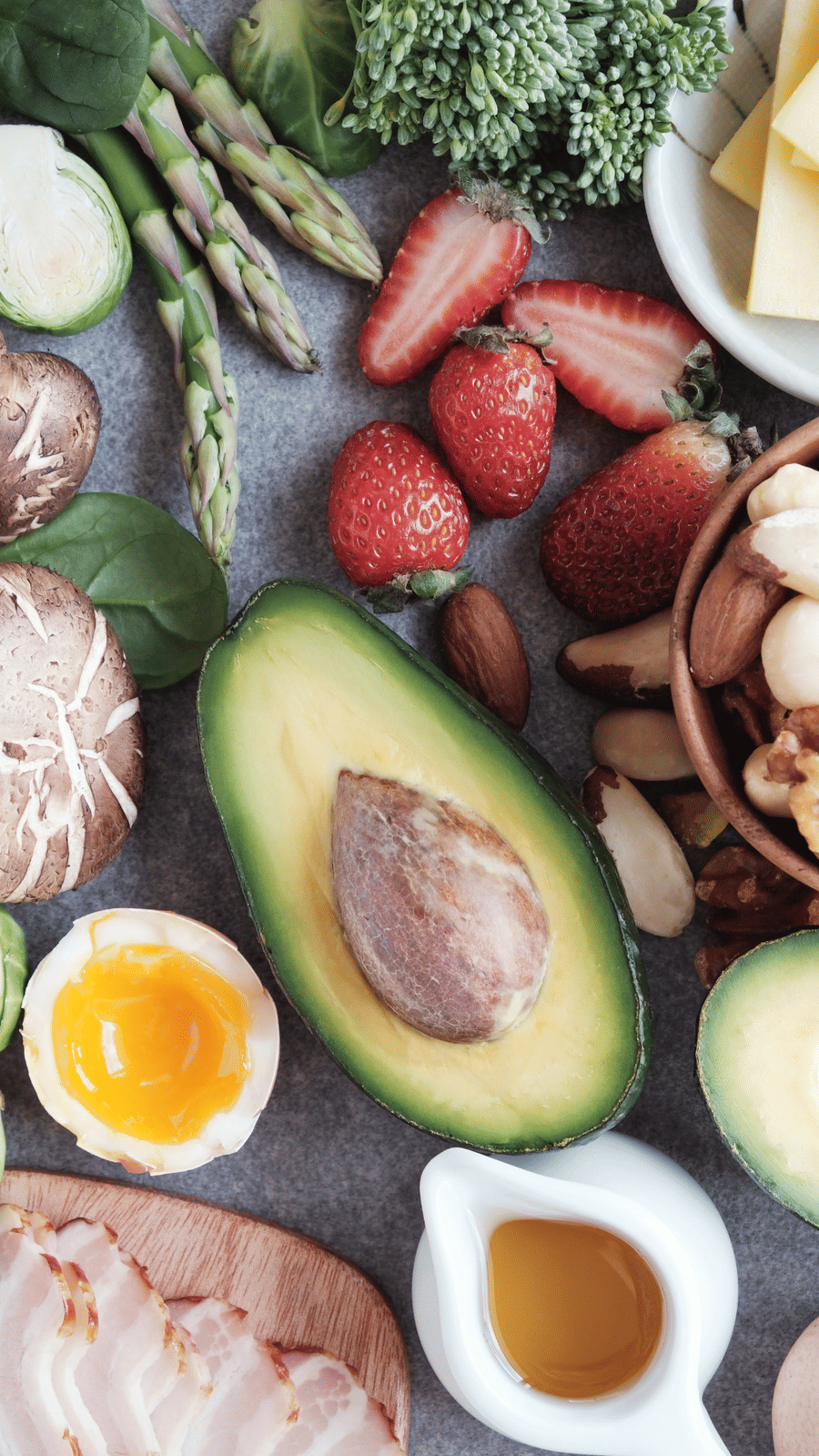 Fruits like strawberries, avocados and brussels sprouts kept next to each other near a container with liquid