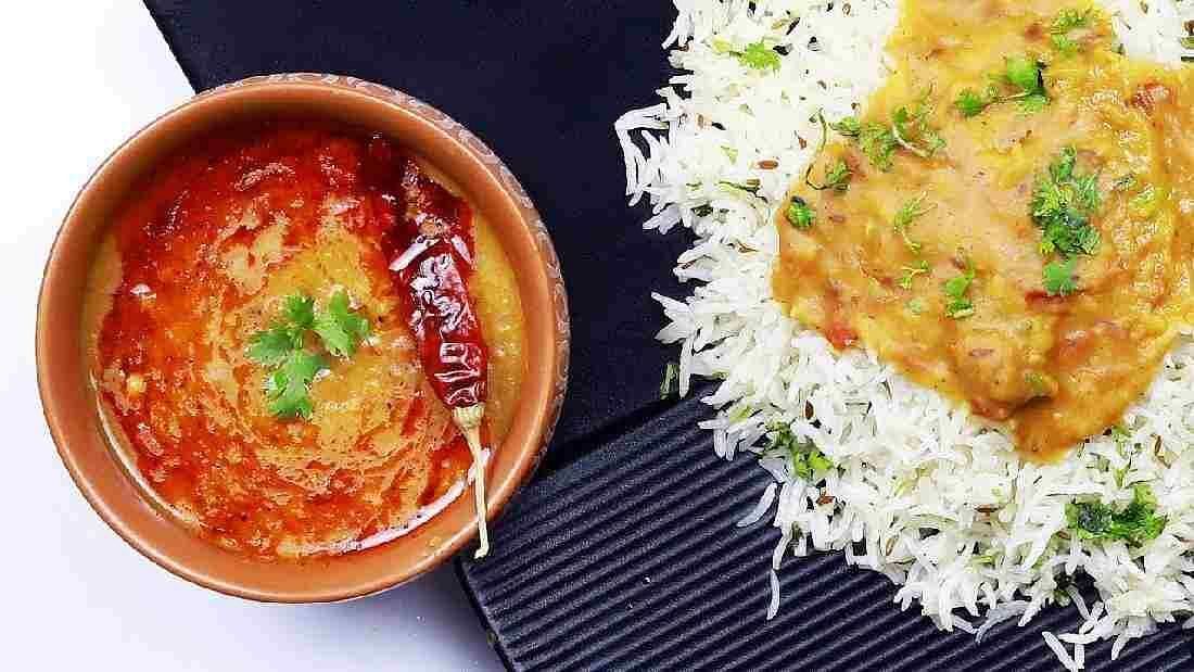 An image of a rice dish with a bowl filled with dal on the side - Motel Divine International, Roorkee
