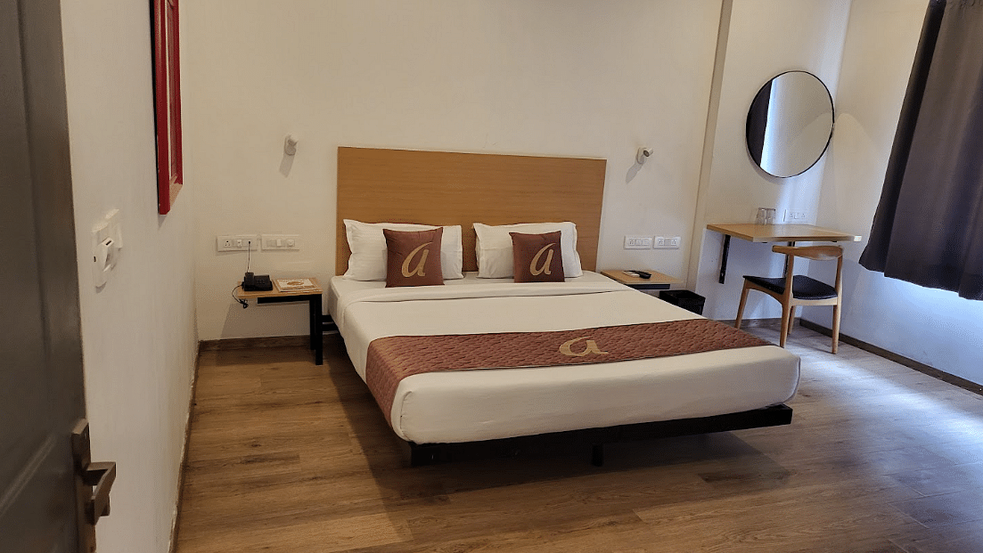 A cosy hotel room with a neatly made double bed, soft lighting, and a large window with dark curtains - Astra Hotels & Suites, Sarjapura