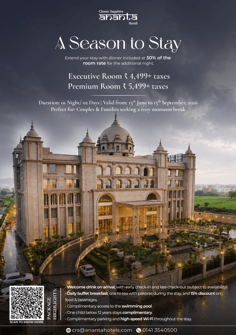 A modern multi story hotel building with glowing lights reflecting in a large outdoor swimming pool during an overcast day, highlighting holiday packages and rooms near Ranakpur.