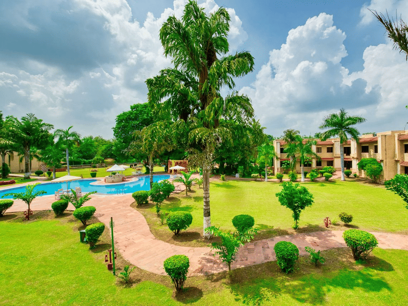 Landscaped garden with walking paths, palm trees, outdoor pool and resort buildings at Clarks Khajuraho.