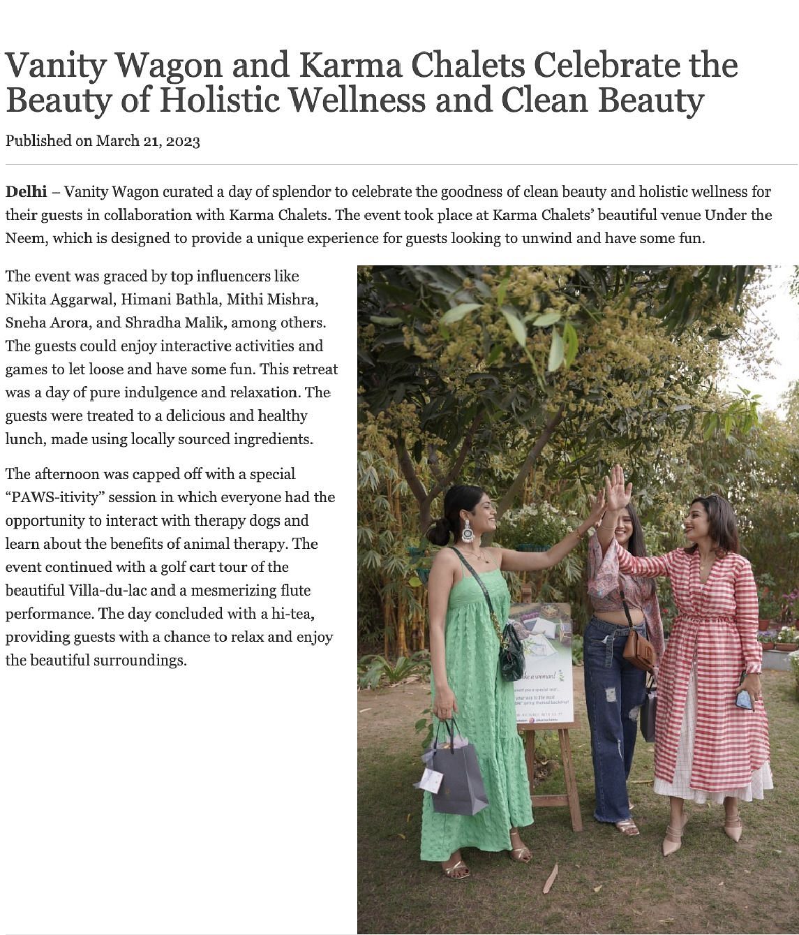 Three women at Karma Chalets' Under the Neem venue high-five during a wellness event with Vanity Wagon, surrounded by greenery and decor.