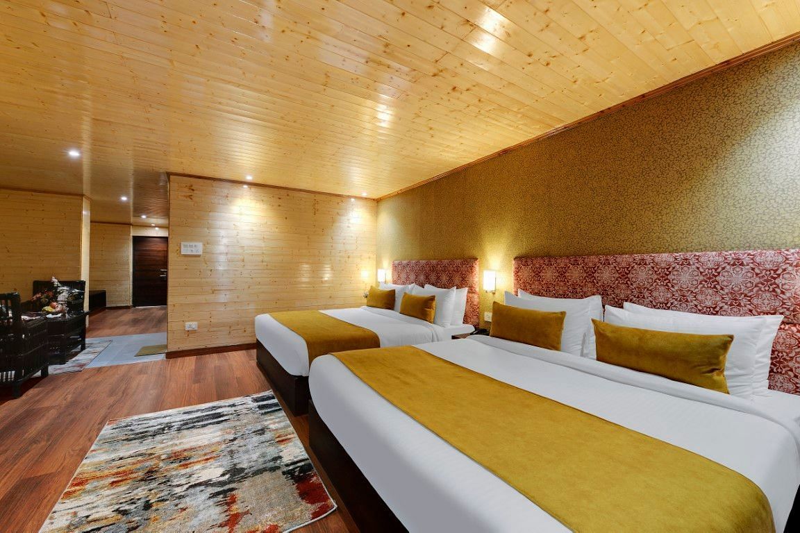 Image of two king size bed in a expansive room with a yellow blanket and wooden furnishing | Yashshree Lachung