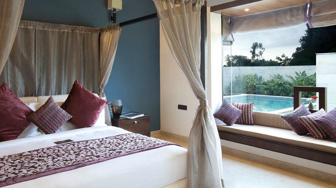 Interior view of a room at The Serai Chikmagalur featuring a plush bed placed next to a window with pool view