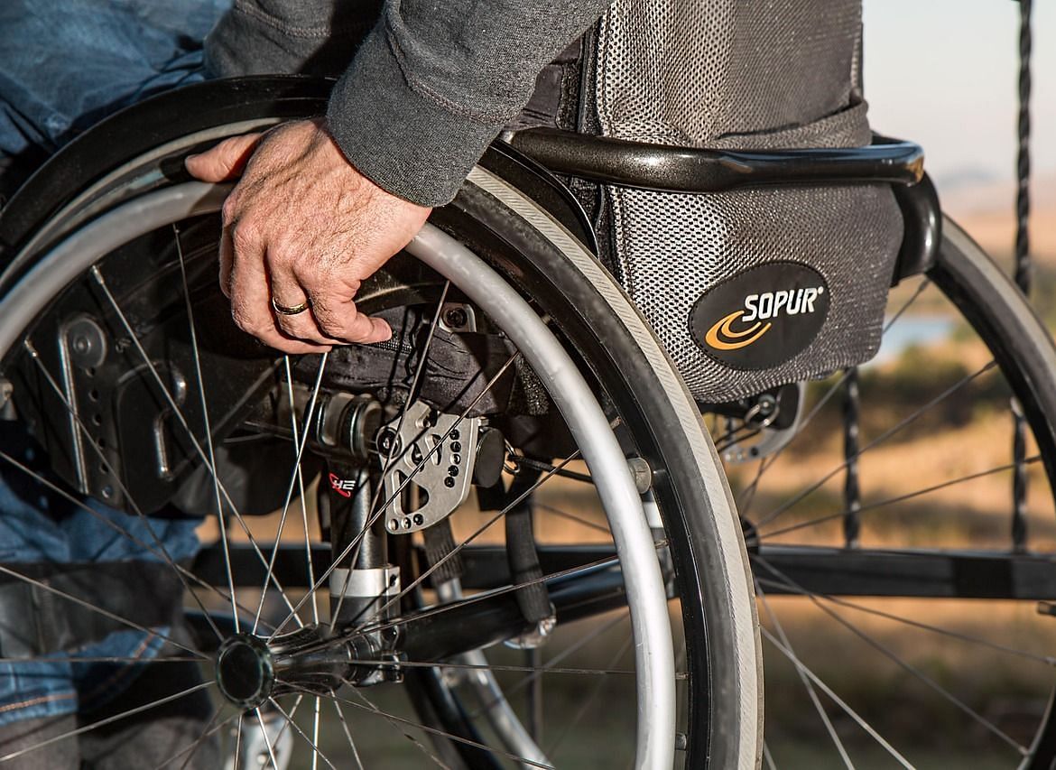 A close-up view of a wheelchair with a person's hand resting near the wheel